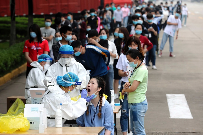 Workers line up for medical workers to take swabs for the coronavirus test at a large factory in Wuhan.